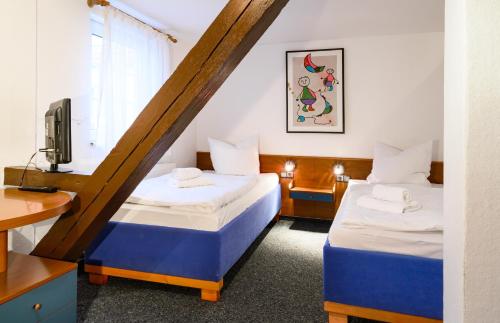 a hotel room with two beds and a tv at Vinetahotel Stadt Barth in Barth