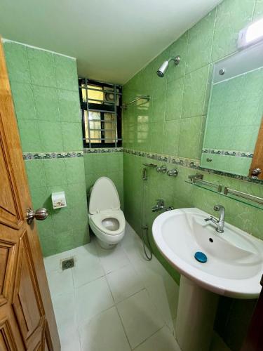 a green bathroom with a toilet and a sink at Modern 3BR Flat,Bashundhara ,AC, Wi-Fi, KeyHost Homes in Dhaka
