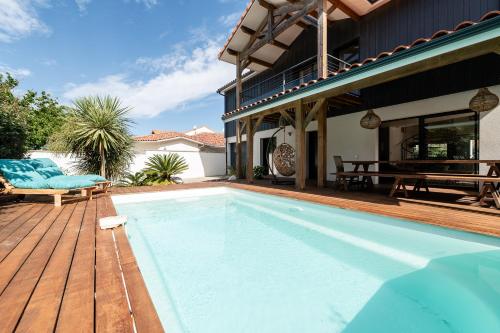 una piscina en una terraza de madera al lado de una casa en Villa Douceur d'Océane, en Biscarrosse