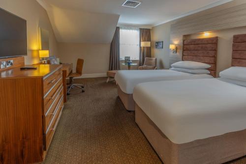 a hotel room with two beds and a television at Cheltenham Chase Hotel & Spa in Cheltenham