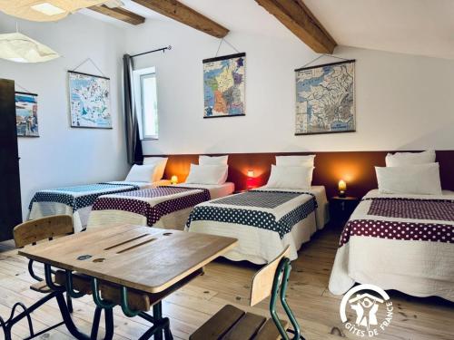 Cette chambre comprend 4 lits et une table en bois. dans l'établissement Gîte de caractère La Grange Saint Papoul, à Saint-Papoul