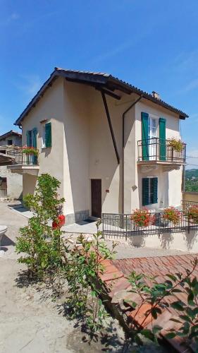 a small white house with green windows and a balcony at Casa storica di Sant'Andrea by Italita in Calamandrana