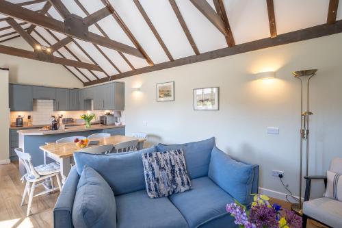 a living room with a blue couch and a kitchen at Canute Cottages - Cullimers Cottage in Chidham