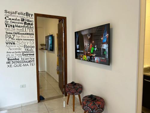 a room with a television on a wall with a chair at BORA BORA RESIDENCE in Joinville