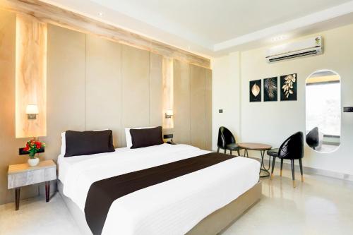 a bedroom with a large bed and a table and chairs at Super Townhouse ISBT Dehradun in Dehradun
