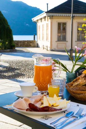 a table with a plate of food and a drink at Hotel Il Portico by LVG Hotel Collection in Cannobio