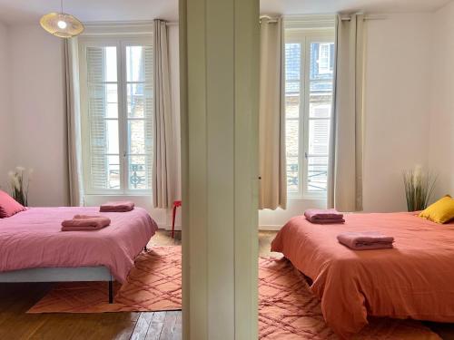 a bedroom with two beds and two windows at Magnifique T3 en plein centre ville de Poitiers in Poitiers
