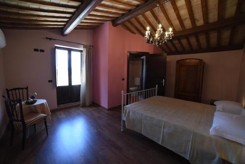 a bedroom with a bed and a table and a chandelier at Agriturismo " La Valle degli Ulivi" in Vacri