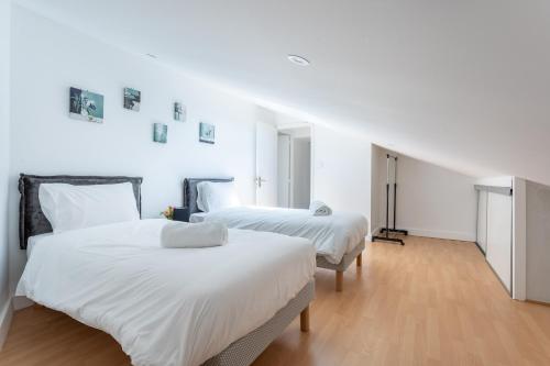 two beds in a room with white walls and wood floors at Orcines -Appt Lumineux & calme - Vulcania à 10 min in Orcines