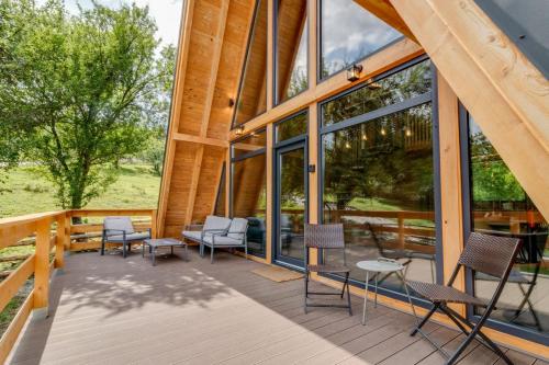 a wooden deck with chairs and tables and windows at Old Nut Cabin in Teşila