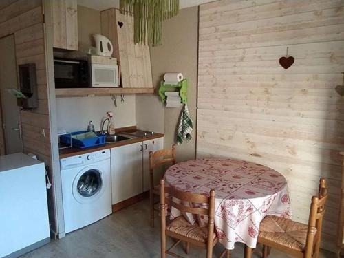une cuisine avec une table et une machine à laver dans l'établissement Studio cabine 26m² avec balcon sud-ouest à Barcelonnette - FR-1-804-45, à Barcelonnette