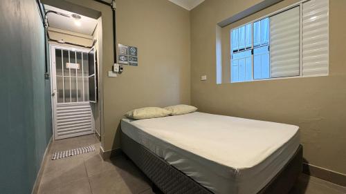 a small room with a bed and a window at Suíte 05 • Praia das Pitangueiras in Guarujá