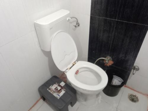 a bathroom with a toilet with a newspaper on it at Family Room in Indore