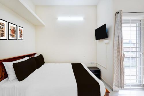 ein weißes Schlafzimmer mit einem Bett und einem Fernseher in der Unterkunft Super Collection O Sholinganallur Chennai Formerly Nimalan Residenc in Chennai