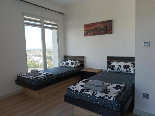 two beds in a room with a window at 33rd Floor Twin Apartments & 7th Floor Apartment In Cevahir Sky City Complex With Pool, Spa, Fitness and Parking Included In Price in Skopje