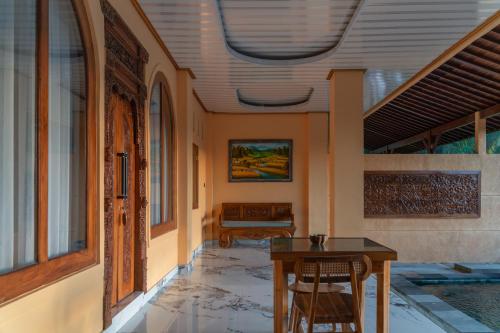 a hallway with a table and chairs in a building at Grand Campuhan in Tegalalang