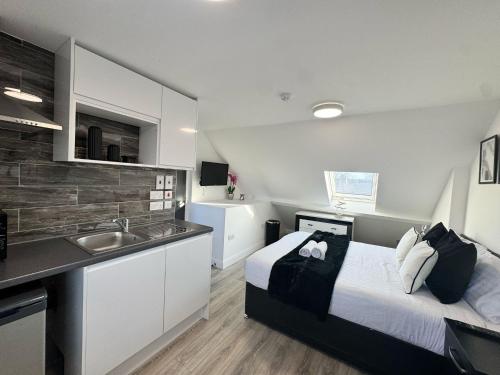 a bedroom with a bed and a kitchen with a sink at The 37 Suites in Ponders End