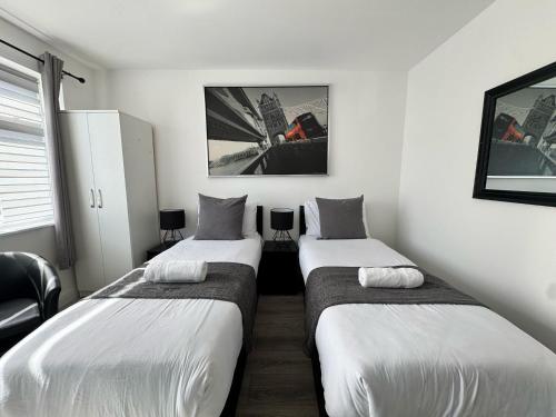 two beds in a room with white walls at The 37 Suites in Ponders End