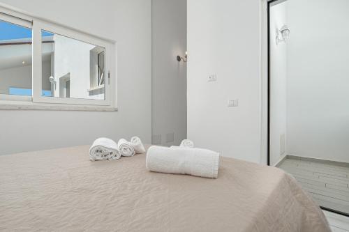 a white bedroom with a bed with towels on it at Villa Ada in Golfo Aranci