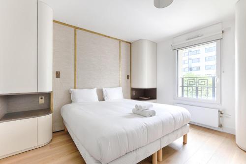 une chambre avec un grand lit blanc et une fenêtre dans l'établissement Appartement de luxe avec terrasse 3BR Levallois, à Levallois-Perret