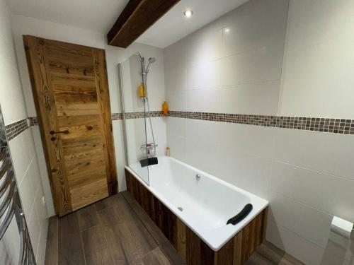 eine Badewanne im Bad mit einer Holztür in der Unterkunft Beautiful chalet with panoramic views in Samoens walking distance to the village in Samoëns