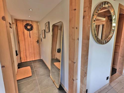 un couloir avec un miroir mural dans l'établissement Chalet rénové pour 10 personnes au Chinaillon avec bain nordique - FR-1-458-218, au Grand-Bornand
