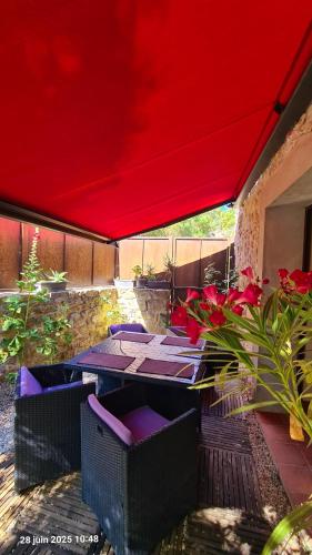 - une table et des chaises sous un parasol rouge sur la terrasse dans l'établissement Villa Misanid écrin de verdure à 15mm de la cité de Carcassonne, à Mas-des-Cours