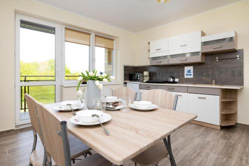 a kitchen and dining room with a wooden table and chairs at Peaceful Apartment Wrzosowo Bay with Parking by Noclegi Renters in Wrzosowo