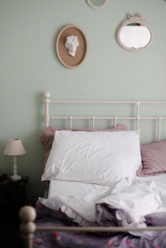 a bed with white pillows and two mirrors on the wall at Casa Montalgallo in Lucignano