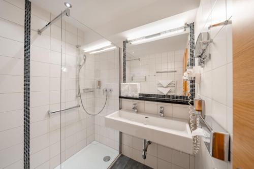 a bathroom with a sink and a shower and a mirror at Familotel Amiamo in Zell am See