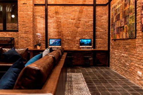a living room with a leather couch and two monitors at Aquarius Hotel and Urban Resort in Phnom Penh