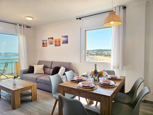 a living room with a table and chairs and a couch at Apartamento Celeste frente al mar in L'Escala