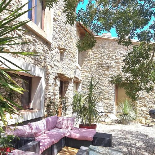un canapé assis devant un bâtiment en pierre dans l'établissement Villa Misanid écrin de verdure à 15mm de la cité de Carcassonne, à Mas-des-Cours