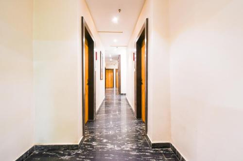 an empty hallway with white walls and black tile floors at Super Townhouse Near Marine Drive in Puri