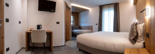 a bedroom with a bed and a desk and a television at Oltre Alpine Hotel in Bormio