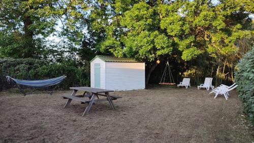 a hammock and a picnic table and a shed at Mobil-home climatisé dans parc résidentiel avec piscine in Saint-Cyr-en-Talmondais