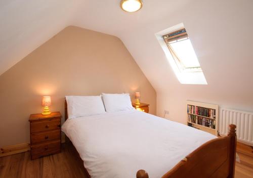 a bedroom with a large white bed and a window at The Hut at Baywatch Bed & Breakfast in Renvyle