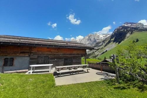a picnic bench in front of a log cabin at Chalet at the foot of the Nordic domain in La Clusaz