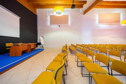 an empty lecture hall with yellow chairs and a podium at Falkensteiner Club Funimation Garden Calabria in Curinga