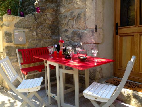 - une table rouge avec deux chaises et des verres à vin dans l'établissement La Maisonnette romantique, à Uzès