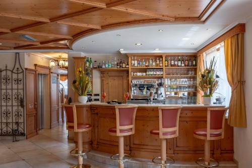a kitchen with a bar with red stools at Beverly Alps Hotel & Spa in Pinzolo