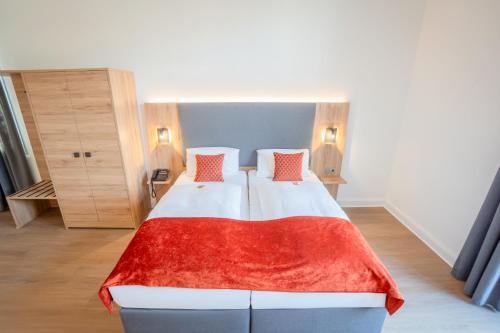 a bedroom with a large bed with a red blanket at Rheinhotel Schulz in Unkel