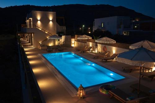 a swimming pool at night with chairs and umbrellas at Yucca Calma in Rhodes Town