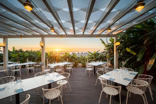a restaurant with white tables and chairs on a deck at Falkensteiner Club Funimation Garden Calabria in Curinga