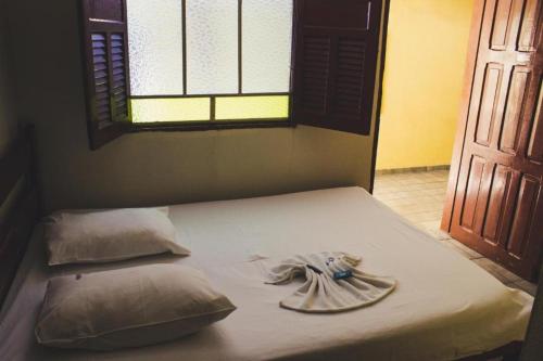 a bed with a towel on it with a window at Hotel Santo Antoninho in Goiânia