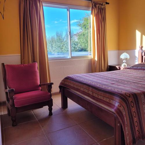 a bedroom with a bed and a red chair and a window at CASA EN VALLE GRANDE Country Club Solar Del Valle in San Rafael