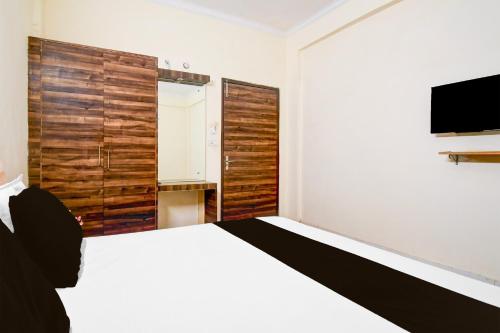 a bedroom with a white bed and a television at OYO Flagship hotel vasundhara inn in Lucknow
