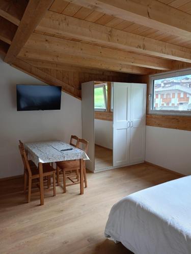 a bedroom with a bed and a table and a tv at Tre Cime Apartments - monolocali in Auronzo di Cadore