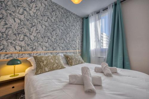 a bedroom with a white bed with pillows and a window at Le Perroquet - Parking - Campus in Saint-Martin-dʼHères