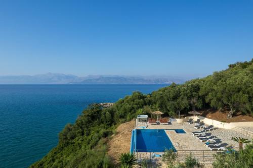 a view of a swimming pool and the ocean at Beachfront Villa Seasun by PosarelliVillas in Agios Spyridon Corfu